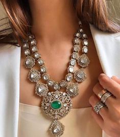 a woman wearing an elaborate necklace and matching ring is holding her hand up to her chest