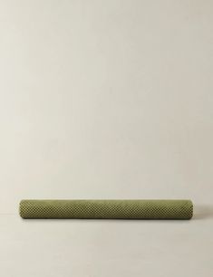 a green yoga mat sitting on top of a white floor next to a black object