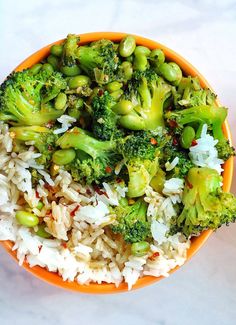 a bowl filled with rice and broccoli on top of a white countertop