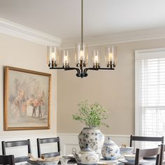 Illuminate your home with this exquisite 5-light black gold pendant chandelier. This modern fixture features a central black metal rod with five elegantly curved arms, each supporting a clear seeded glass cylinder shade. Lighting Above Dining Table, Dining Table Chandelier Modern, Black Chandelier Dining Room, Light Above Dining Table, Seeded Glass Pendant Light, Dining Table Chandelier, Lights For Dining Room, Seeded Glass Pendant, Glass Pendant Lights