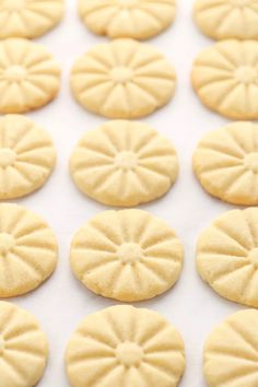 small cookies are arranged in rows on a white surface