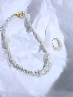 a white necklace and earring sitting on top of a piece of paper