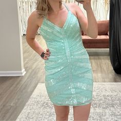 a woman taking a selfie in front of a mirror while wearing a green dress