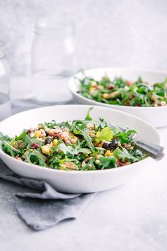 two white bowls filled with salad on top of a table