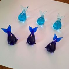 six blue glass figurines sitting on top of a white paper with lights around them