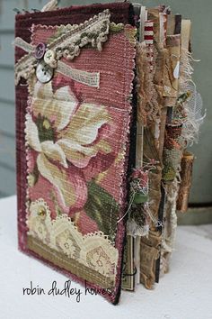 an altered book with flowers and laces on the pages is sitting on a table