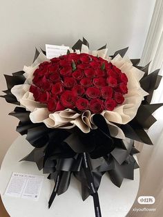 a large bouquet of red roses sitting on top of a white table