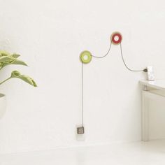 a white room with a potted plant on the floor and a wall mounted light