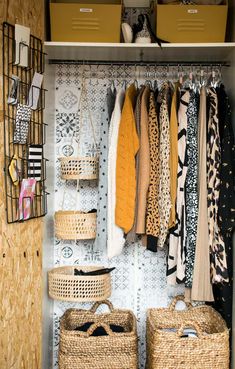 an organized closet with baskets and clothes hanging on the wall next to two wicker baskets