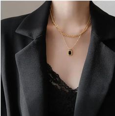 This necklace embodies a harmonious blend of textures and colors, with layers of lustrous gold stainless steel chains that elegantly cascade and culminate in a striking bezel-set black or white stone pendant. The contrast between the radiant gold and the deep black stone exudes a sense of intrigue and luxury, making it an ideal accessory for elevating any ensemble. With its versatile design and meticulous craftsmanship, this necklace becomes a symbol of refined elegance and modern style.Stainles Black Gold-plated Adjustable Chain Jewelry, Black Pendant Necklace With Chain, Black Metal Pendant Chain Necklace, Formal Black Gold Plated Necklace, Formal Black Gold-plated Necklace, Elegant Double Chain Pendant Necklace, Elegant Pendant Necklace With Double Chain, Trendy Black Jewelry With Gold Chain, Elegant Black Gold Plated Chain Necklace