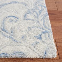 a blue and white rug on top of a wooden floor next to a hard wood floor