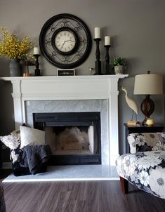 a living room with a fireplace, chair and clock on the wall above it's mantle