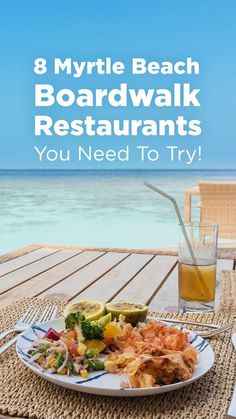 a white plate topped with food on top of a wooden table next to the ocean