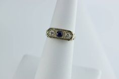 This is a 18K WG Art Deco Diamond and Sapphire 3 stone ring. Central round sapphire flanked by brillant cut diamonds. 3.5 mm stones top pierced millegrained sides, pierced and engraved florals, circa 1910, size 6, weight 2.7 grams. Art Deco Oval Multi-stone Sapphire Ring, Art Deco Sapphire Hallmarked Jewelry, Blue Sapphire Ring, Art Deco Style For Gift, Art Deco Platinum Multi-stone Rings, Art Deco Multi-stone Sapphire Jewelry, 3 Stone Ring, Round Sapphire, 3 Stone Rings, Stone Top