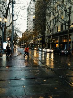 people are walking down the street in the rain