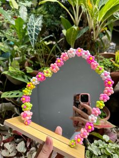 a hand holding up a mirror with beads on it and a camera in the background