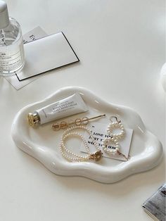 a white tray topped with lots of jewelry next to a bottle of water and a pair of earrings