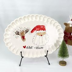 a white plate with santa claus and reindeer on it next to a small christmas tree