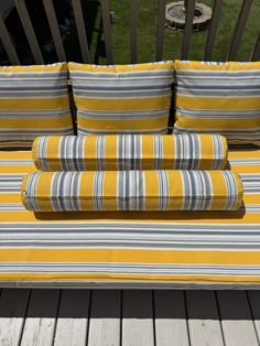 a yellow striped couch sitting on top of a wooden deck