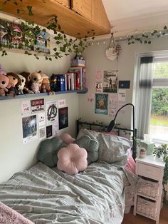 a bed with pillows and stuffed animals on top of it in a bedroom next to a window