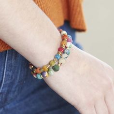 a close up of a person wearing a bracelet with beads on their wrist and hand