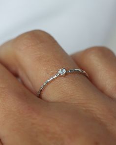 a woman's hand with a diamond ring on her left hand, wearing a white gold band