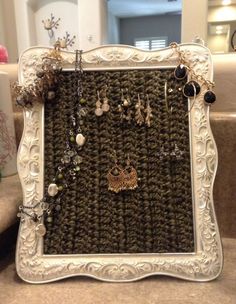 a white frame holding several pairs of earrings and necklaces on a counter top next to a sink