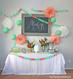 a table topped with paper flowers and decorations next to a chalkboard sign that says mintt & be