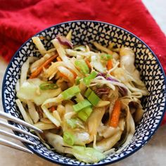 a bowl filled with coleslaw and carrots on top of a table next to a red towel