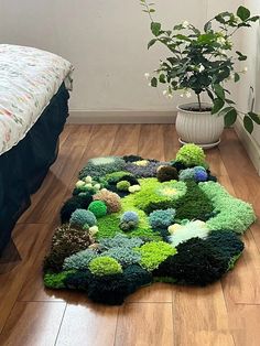 there is a rug made out of green plants on the floor next to a bed