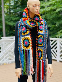 a mannequin wearing a multicolored crocheted scarf with tassels