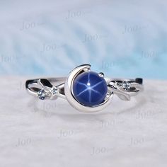 a ring with a blue stone in the middle on top of a white cloth background