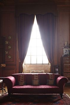 a red couch sitting in front of a window