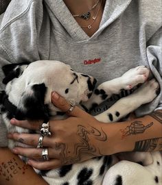 a woman is holding two dalmatian puppies in her arms, both with tattoos on them