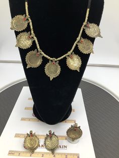 This complete vintage coin set includes a necklace, a pair of earrings, and a ring, is an epitome of tradition, as the design of the set is inspired by the Afghani Kuchi ornaments. The rusty gold toned set is embellished with dangling elements, adorned with intricate patterns and archaic motifs. The pair of earrings, coin shaped, complete the set in an astonishing manner, complimented by the antique ring in the identical design. You can pair this complete traditional set with any traditional or Handmade Ceremonial Jewelry For Festivals, Gold Coin Pendant Necklace For Festival, Ceremonial Brass Matching Earrings, Adjustable Antique Finish Wedding Jewelry, Antique Finish Adjustable Wedding Jewelry, Bohemian Jewelry For Ceremonial Festival, Bohemian Festival Jewelry For Ceremonial Occasions, Antique Metal Jewelry For Festivals, Nickel-free Antique Gold Metal Jewelry