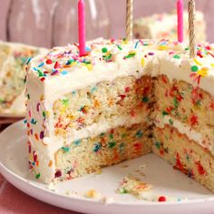 a cake with white frosting and colorful sprinkles on it is cut in half