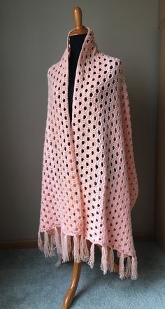 a pink crocheted shawl on a mannequin