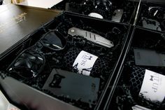 several pairs of sunglasses are in a black case with tags on them and some other items