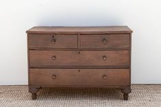 an old wooden dresser sitting on top of a carpeted floor next to a white wall