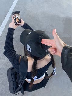 a woman holding up her cell phone to take a selfie while sitting on the ground