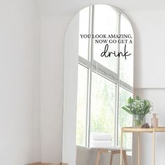 an arched window in a white room with the words you look amazing, now go get a drink