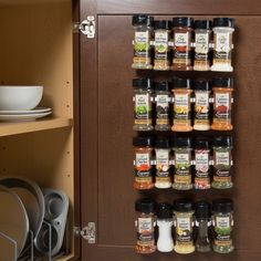 a spice rack with spices on it in a kitchen next to plates and utensils