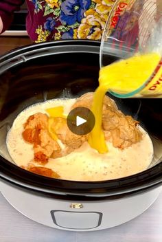 someone pouring orange juice into a crock pot filled with meat and cheese in the slow cooker