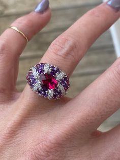 The center stone in this ring is just stunning with deep pink saturation of the stone. . The center piece is a genuine pink tourmaline measuring 7.75mm x 5.75mm, and it has a beautiful checkerboard cut for additional sparkle. The pink tourmaline is accompanied by genuine deep purple amethyst, pale rose amethysts, and additional pink tourmaline round stones.  There are round diamonds totaling approximately .16ctw G/SI1 This ring is super comfortable.  It slides so nicely on the finger and feels v Luxury Pink Gemstone With Center Stone, Luxury Pink Ruby Ring With Accent Stones, Luxury Oval Ruby Ring With Gemstone, Luxury Pink Amethyst Ring With Accent Stones, Luxury Pink Amethyst Gemstone Ring, Pink Amethyst Ring For Formal Occasions, Elegant Pink Ruby Gemstones, Luxury Pink Multi-stone Ruby Ring, Formal Pink Amethyst Ring With Gemstone Accents