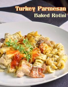 a white plate topped with pasta and meat covered in sauce next to a glass of wine