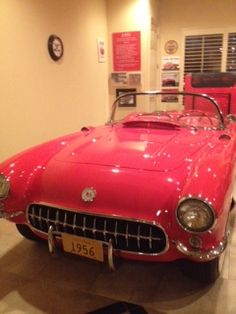 an old red car is on display in a museum