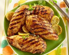 grilled chicken with lemons and herbs on a green plate