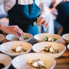 a person in an apron is preparing food on a table with bowls and spoons