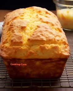 a loaf of bread sitting on top of a cooling rack next to a glass bowl