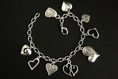 A collection of silver plated decorative heart charms have been dispersed around a shimmering silver plated bracelet chain in this handmade charm bracelet. This heart charm bracelet is then completed with a lobster clasp and a 1/2 inch of chain at the end for adjustable sizing. Charms in this bracelet include an assortment of nine decorative heart charms. ● Sizing ● To determine your bracelet size, do a snug measurement of your wrist's circumference, then add 1/2 an inch. 6 to 6.5 inches (15cm - Elegant Handmade Metal Heart Bracelet, Handmade Metal Charm Bracelet For Valentine's Day, Silver Metal Heart Bracelet With Charms, Nickel-free Silver Heart Bracelet For Anniversary, Elegant Silver Charm Bracelet With Heart Beads, Silver Charm Bracelet With Heart Beads, Nickel-free Metal Charm Bracelet For Valentine's Day, Silver Heart Beads Bracelet For Jewelry Making, Silver Heart Chain Bracelet For Valentine's Day